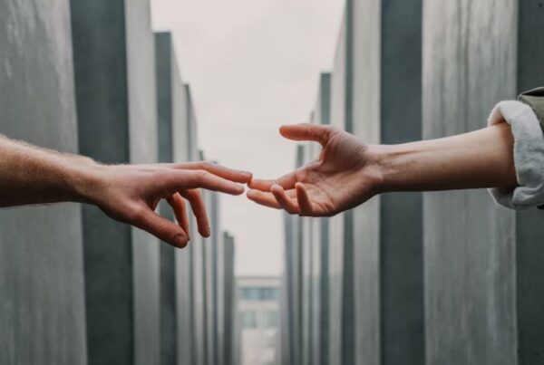 Hands reaching out to help, with a landscape of stone buildings in the background.