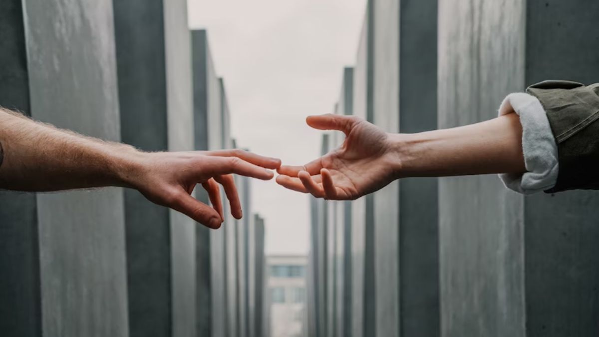 Hands reaching out to help, with a landscape of stone buildings in the background.