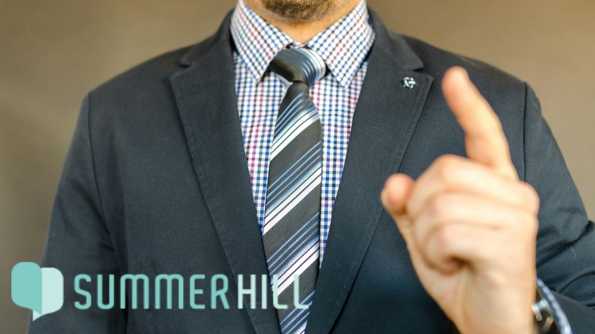 Man in a suit pointing a finger, appearing successful yet highly stressed.