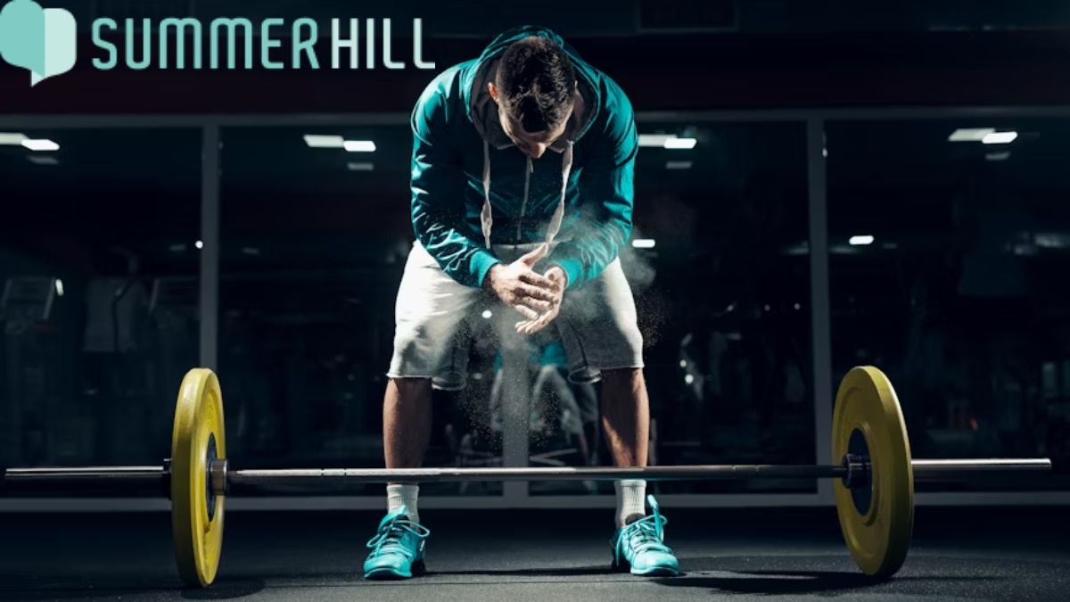 Physical and mental health, a man prepares to lift heavy steel weights during a gym workout.