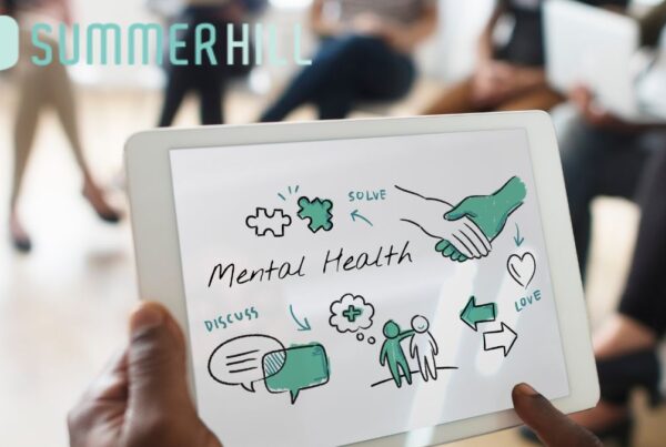 A tablet displaying the words 'Mental Health Awareness' sits on a notepad during a therapy awareness session.