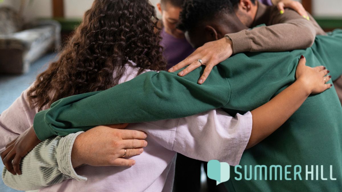 A group of young people share a group hug, symbolizing unity and cooperation for mental health awareness.