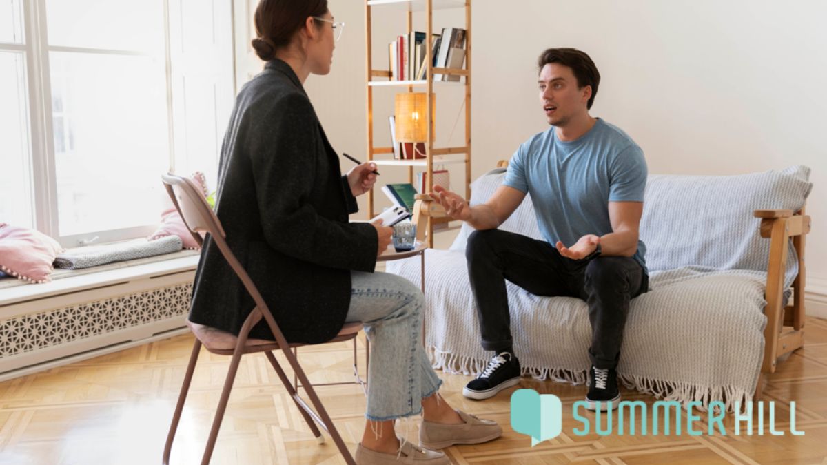 A young man engages actively in talk therapy, participating and sharing his experiences during a CBT session for bipolar disorder.