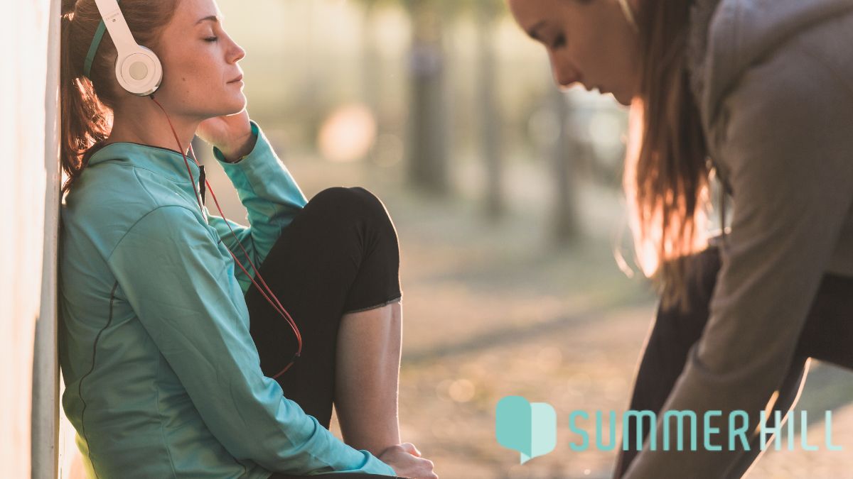 Physical and mental health, a woman wearing headphones relaxes and listens to music after a workout.