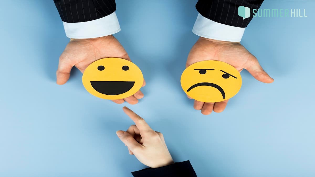 Sad and happy emoji in each hand