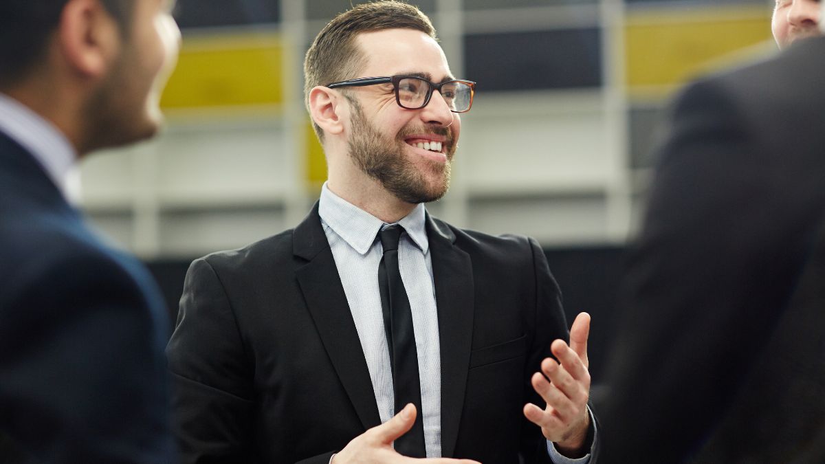 Masking Anxiety: A man in a suit speaks confidently to a group on the mezzanine of a skyscraper.