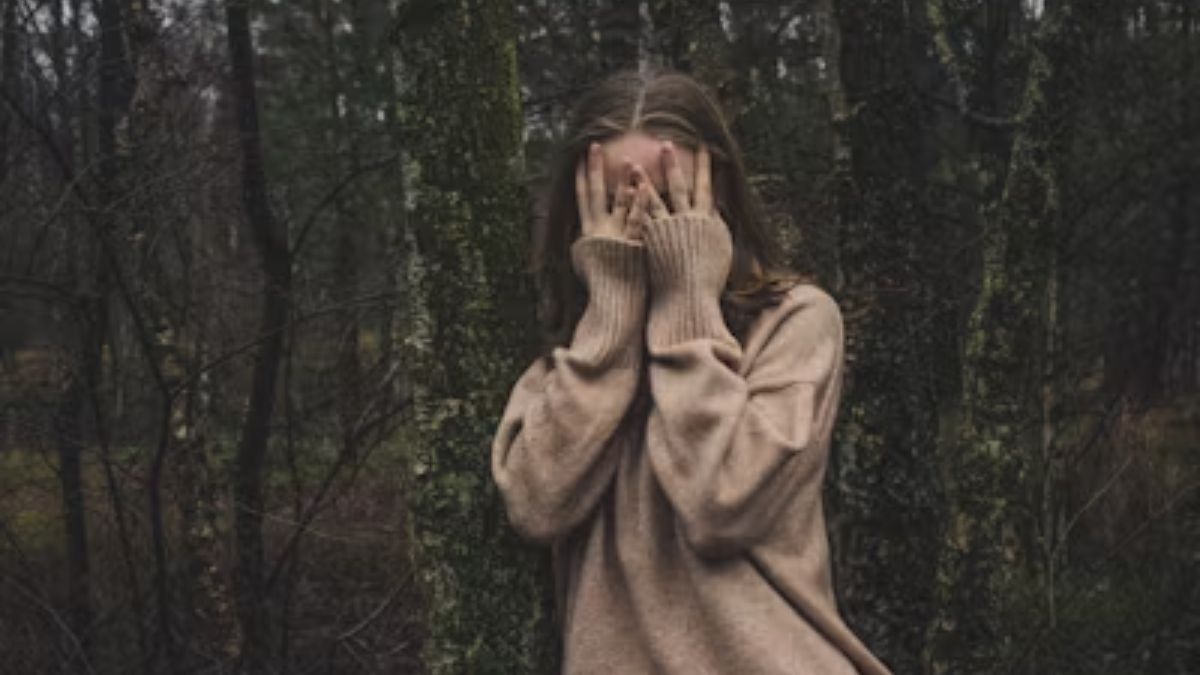 Masking Anxiety: A woman in a forest scene covers her face, illustrating the condition.