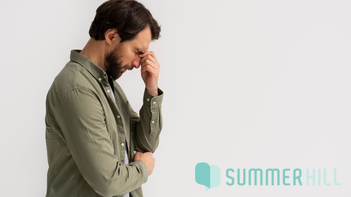 A man in a casual shirt scrunches his forehead and touches it with his hand, showing deep frustration, illustrating how therapy can feel hard.