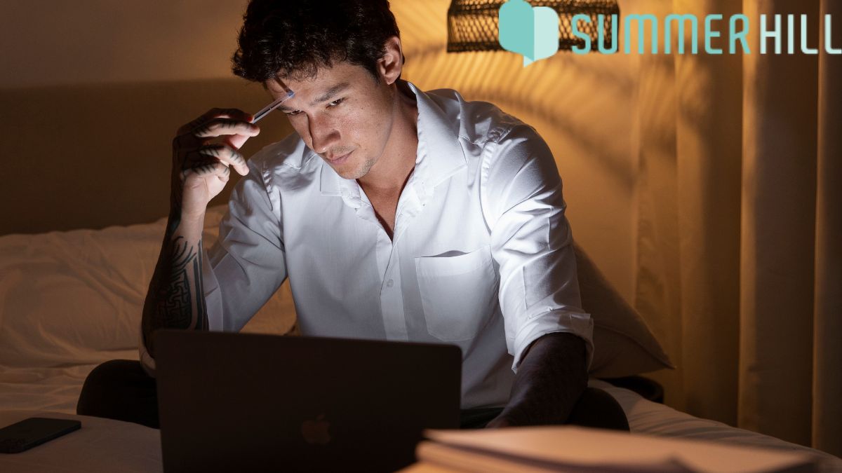 A man stares at his computer screen late at night, struggling with overthinking before bedtime as he tries to prepare for sleep.