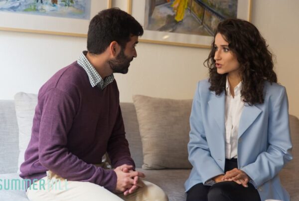A couple in discussion while sitting on a couch.