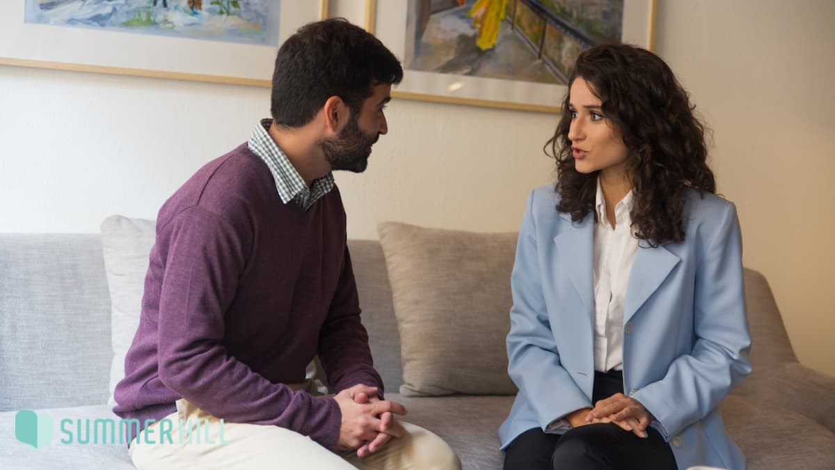 A couple in discussion while sitting on a couch.