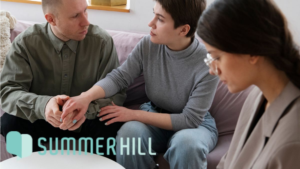 A couple sits together in a clinic participating in DBT therapy session.