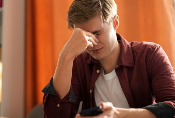 A man sits near a table, looking frustrated during DBT therapy in afternoon light.