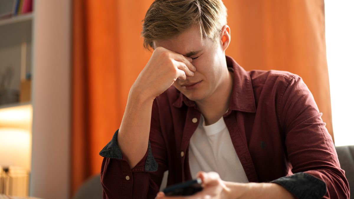 A man sits near a table, looking frustrated during DBT therapy in afternoon light.